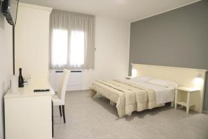 a white bedroom with a bed and a desk at B&B Allison Tropea in Tropea