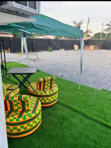 eine Gruppe von Stühlen auf dem Gras unter einem Zelt in der Unterkunft Colourful Ghanaian Cottage in Lateman