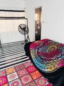 Schlafzimmer mit einem Bett mit einem Teppich und einem Ventilator in der Unterkunft Colourful Ghanaian Cottage in Lateman