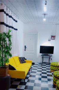 ein Wohnzimmer mit einem gelben Sofa und einem TV in der Unterkunft Colourful Ghanaian Cottage in Lateman