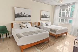 1 dormitorio con 2 camas y silla verde en Urban Retreat - Location Pool Gym & Parking, en Miami