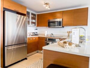 a kitchen with wooden cabinets and a stainless steel refrigerator at Palm Place Heart of Miami with Parking Pool and Gym in Miami