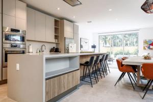 uma cozinha com armários brancos e uma mesa e cadeiras em The Modernista 2 - Large Townhome with Pool and Parking em Miami