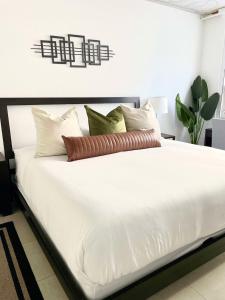 een bed met witte lakens en kussens in een kamer bij City Condo in Midtown Wynwood with pool and parking in Miami
