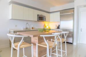 a kitchen with white cabinets and a wooden island with bar stools at Brickell House Dreams - Luxury Stay and Amenities in Miami