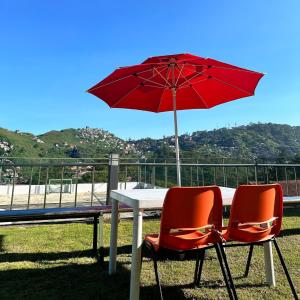 una mesa con 2 sillas y una sombrilla roja en Baguio BELL Staycation, en Baguio