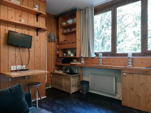 a living room with wooden walls and a television and a desk at Résidence Nova - Studio 2 personnes, proche des pistes et des commerces, au cœur de la station d’Arc 1800 dans le village des Villards MAE-2572 in Arc 1800