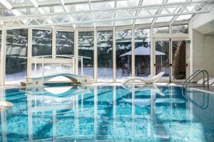 a swimming pool in a building with a large window at Golf Hotel in Folgaria