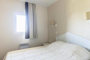 um quarto com uma cama branca e uma janela em Résidence Le Thabor - maeva Home - Appartement 2 Pièces 5 Personnes - Sél 794 em Le Désert