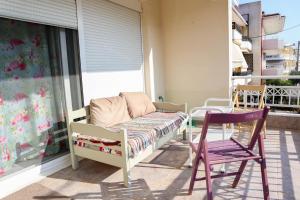 een veranda met een bed, een stoel en een raam bij Pepi's Cozy Apartment in Alexandroupoli