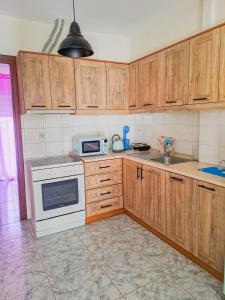 een keuken met houten kasten en een witte kookplaat bij Pepi's Cozy Apartment in Alexandroupoli
