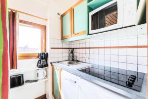 a small kitchen with a sink and a microwave at Résidence Les Chalets des Arolles - maeva Home - Studio 5 Personnes - Séle 004 in La Plagne Tarentaise
