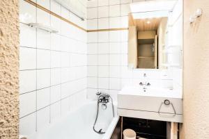 een witte badkamer met een wastafel en een bad bij Résidence Les Chalets des Arolles - maeva Home - Studio 5 Personnes - Séle 004 in La Plagne Tarentaise