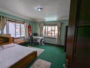 a bedroom with a bed and a desk and windows at Family Home with Rooftop access and Mountain View in Kathmandu