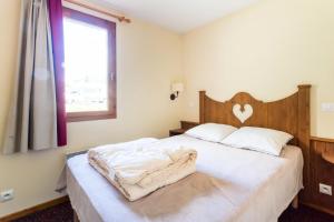 1 dormitorio con 1 cama con cabecero de madera y ventana en Résidence L'Alpaga - maeva Home - Appartement 2 Pièces 7 Personnes - Budge 994, en La Salle-les-Alpes