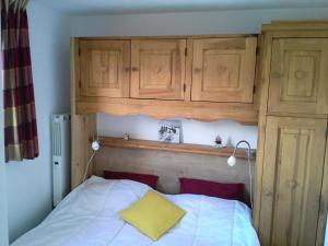 uma cama com armários de madeira e uma almofada amarela em Les Chalets D'arrondaz - 3 Pièces pour 6 Personnes 38 em Modane