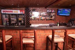 a bar with a brick wall with chairs and a counter at SHERBOURNE LODGE in Kitwe
