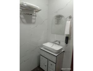 een witte badkamer met een wastafel en een spiegel bij Hotel The Narendra Orchid, Phata in Phata
