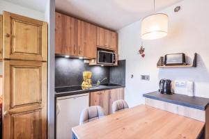 a kitchen with wooden cabinets and a wooden table at Résidence Le Cédrat - maeva Home - Appartement 2 pièces 4 personnes avec 254 in Avoriaz