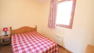 una camera con un letto con una coperta a scacchi e una finestra di Résidence Parc Aux Etoiles - CH19PAE - CHALET DUPLEX 2 CHAMBRES, TERRASSE ET BALCON MAE-2164 a Narreyroux Altre 8 foto