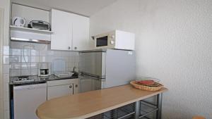 Una cocina con un refrigerador blanco y una mesa. en Résidence Portillo - POR206 - APPT T2 - 5 PERSONNES - VUE PISTES - CENTRE STATION MAE-2294, en Les Prés