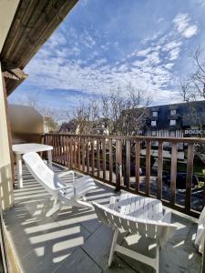 einen Balkon mit zwei weißen Stühlen und einem Tisch in der Unterkunft Appartement charmant bord de mer in Cabourg