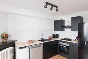 uma cozinha com armários pretos e electrodomésticos brancos em Brussels Benit Ixelles Residence em Bruxelas