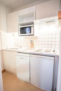 uma cozinha branca com um micro-ondas e um lavatório em Résidence Les Portes De La Vanoise - 2 Pièces pour 6 Personnes 193054 em Villarodin-Bourget