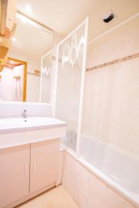uma casa de banho com um lavatório, uma banheira e uma janela em Résidence Les Portes De La Vanoise - 2 Pièces pour 6 Personnes 193054 em Villarodin-Bourget
