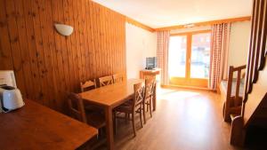 una sala da pranzo con tavolo e sedie in legno di Résidence Parc Aux Etoiles - CH18PAE - CHALET DUPLEX 2 CHAMBRES, TERRASSE ET BALCON MAE-2404 a Narreyroux
