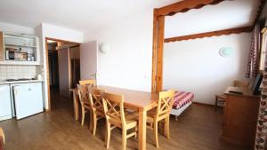 uma cozinha e sala de jantar com uma mesa de madeira e cadeiras em Résidence Parc Aux Etoiles - 4 Pièces pour 7 Personnes 504 em Narreyroux