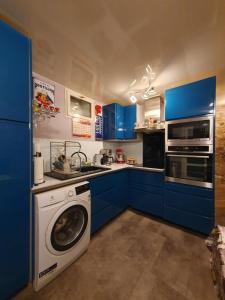een keuken met blauwe kasten en een wasmachine bij Chambre privée avec petit déjeuner dans maison de ville - Saint mandé- Paris in Saint-Mandé