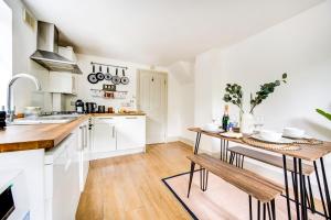 cocina con armarios blancos y mesa de madera en Heart of Hackney - 2bed garden flat sleeps 6 en Londres