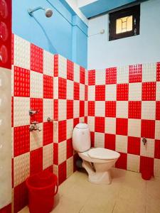 Łazienka z toaletą i czerwono-białą ścianą w kolorze w obiekcie Aurora Inn w mieście Sibsāgar