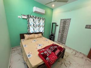 a bedroom with a bed in a room with green walls at Sai Ayush Homestay in Kumbakonam