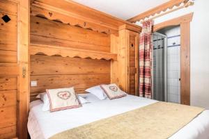 ein Schlafzimmer mit einem Bett mit einer Holzwand in der Unterkunft Résidence La Ginabelle - maeva Home - Appartement 3 pièces 6 personnes - P 604 in Chamonix-Mont-Blanc