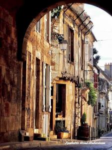 an old building with an arch in a street at La Loupière in Avallon