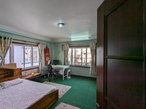 Schlafzimmer mit einem Bett, einem Schreibtisch und Fenstern in der Unterkunft Family Home with Rooftop access and Mountain View in Kathmandu