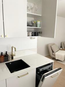 a white kitchen with a sink and a counter at Seaside apt with parking space, close to metro (6mins from city centre) in Helsinki