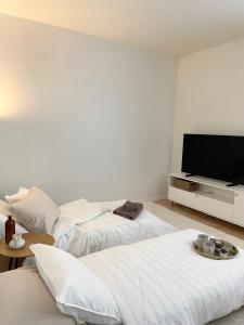 a white room with two beds and a flat screen tv at Seaside apt with parking space, close to metro (6mins from city centre) in Helsinki