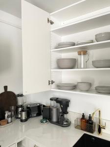 a kitchen with white cabinets and dishes on shelves at Seaside apt with parking space, close to metro (6mins from city centre) in Helsinki