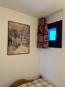 ein Schlafzimmer mit einem Gemälde an der Wand und einem Fenster in der Unterkunft La Balcons d olympie in Les Menuires