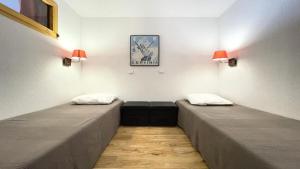 twee bedden in een kamer met lampen aan de muur bij Résidence Dame Blanche - 2 Pièces pour 6 Personnes 574 in Narreyroux