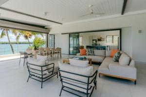 un soggiorno con un divano, sedie e un tavolo di Tamarin Sunset Beach II a Tamarin