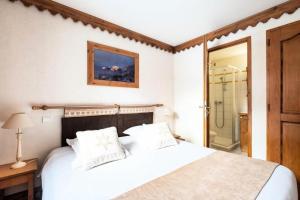 ein Schlafzimmer mit einem weißen Bett und einer Dusche in der Unterkunft Résidence La Ginabelle - maeva Home - Appartement 3 pièces 6 personnes - P 904 in Chamonix-Mont-Blanc