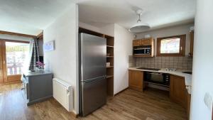 a kitchen with a stainless steel refrigerator and wooden cabinets at Résidence Dame Blanche - 3 Pièces pour 6 Personnes 664 in Narreyroux