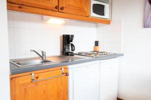 uma cozinha com um lavatório e um micro-ondas em Chalet Arrondaz J - 3 Pièces pour 6 Personnes 193111 em Modane