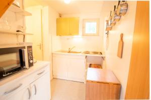 una pequeña cocina con armarios blancos y microondas en Résidence Les Arolles - LES AROLLES - AR40A MAE-3104, en Villarodin-Bourget