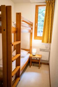 a room with bunk beds and a table and a window at Chalet Arrondaz J - 3 Pièces pour 6 Personnes 193111 in Modane