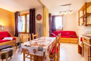 a dining room with a table and a red couch at Quartier La Forêt - maeva Home - Studio 4 Personnes - Sélection MAE-4474 in Valmorel